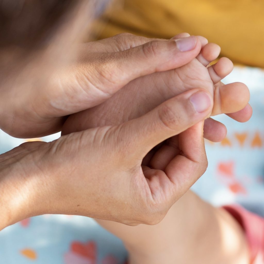 photo illustrant une personne pratiquant de la réflexologie plantaire à un bébé
massage